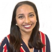 Person with long dark hair wearing a red, white, and navy striped top, posed against a plain white background.
