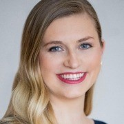 Person with long wavy hair smiling against a plain light background.