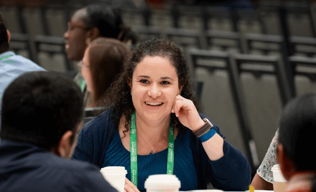 Group of people sitting around a table with coffee cups, engaged in conversation. Text reads: "Pediatric Academic Societies 2025 Meeting. Used with permission."