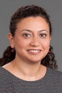 Person wearing a patterned top with a dark gray background.